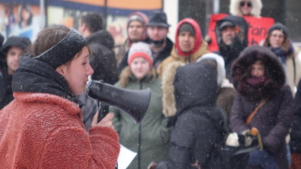 Une femme avec un megaphone devant des manifestants