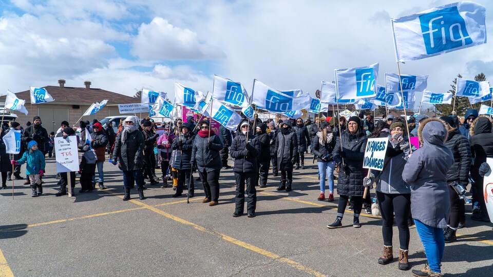 Des membres du Syndicat des professionnelles en soins de la Mauricie et du Centre-du-Québec dehors avec des drapeaux sur lesquels ont peut lire FIQ.