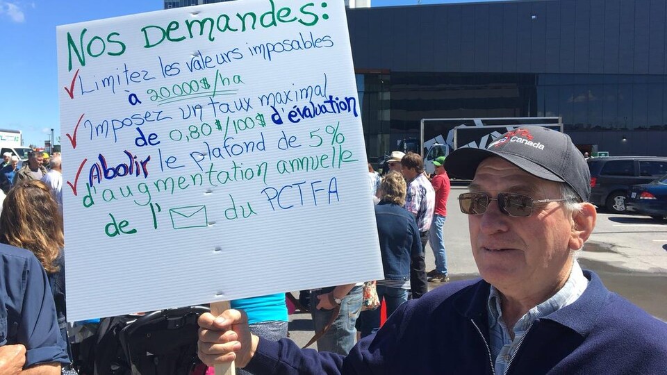 Un homme tient une pancarte énumérant quelques demandes.
