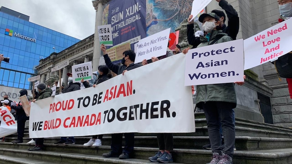 Des manifestants tiennent des affiches avec des slogans contre le racisme anti-asiatique.