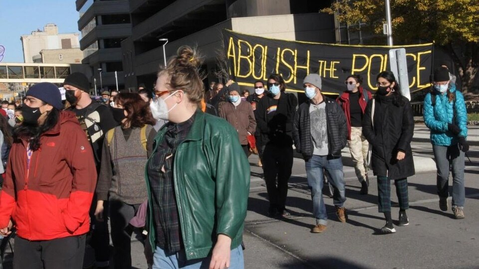 Des gens marchent lors d'une manifestation contre la violence policière à Winnipeg.