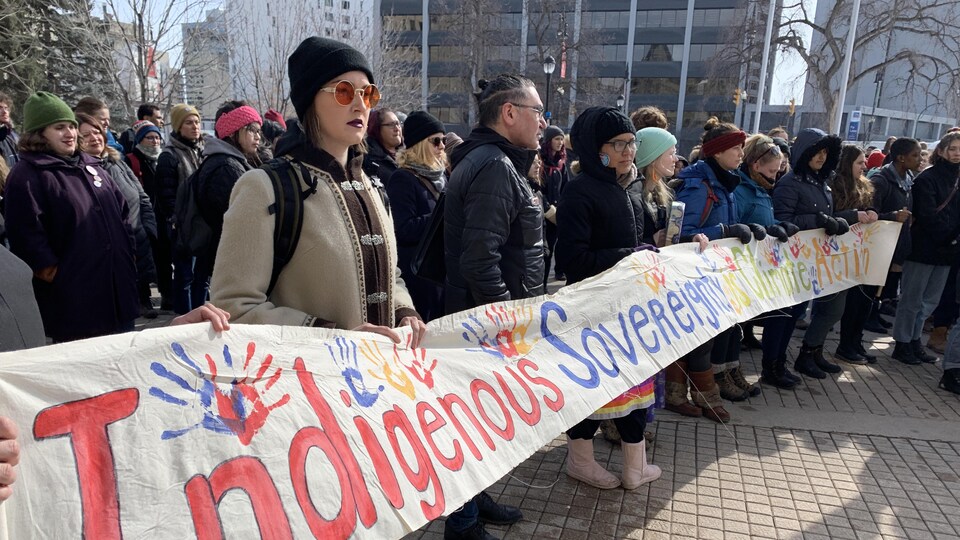 Des manifestants marchent avec une banderole colorée.