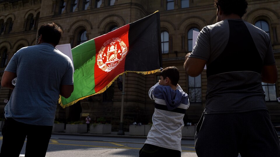 Un enfant brandi un drapeau afghan à Ottawa en été.