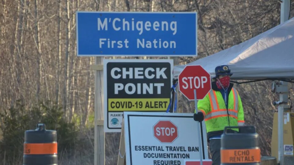 Un homme tient un panneau de signalisation sur lequel est inscrit « stop » à un point de surveillance.