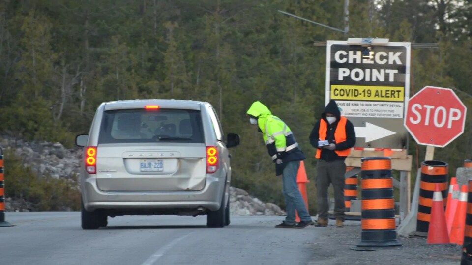 Deux personnes à côté d’un véhicule immobilisé.
