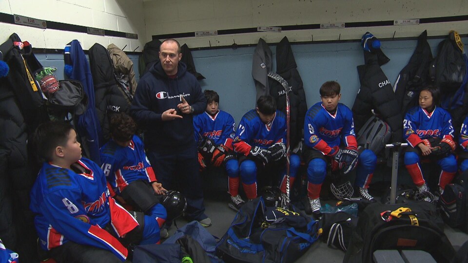 Un entraîneur parle aux hockeyeurs dans la chambre des joueurs.