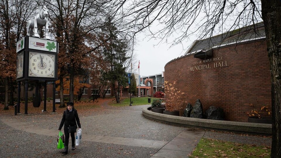 Une femme marche devant l'hôtel de ville de Maple Ridge un jour d'automne.