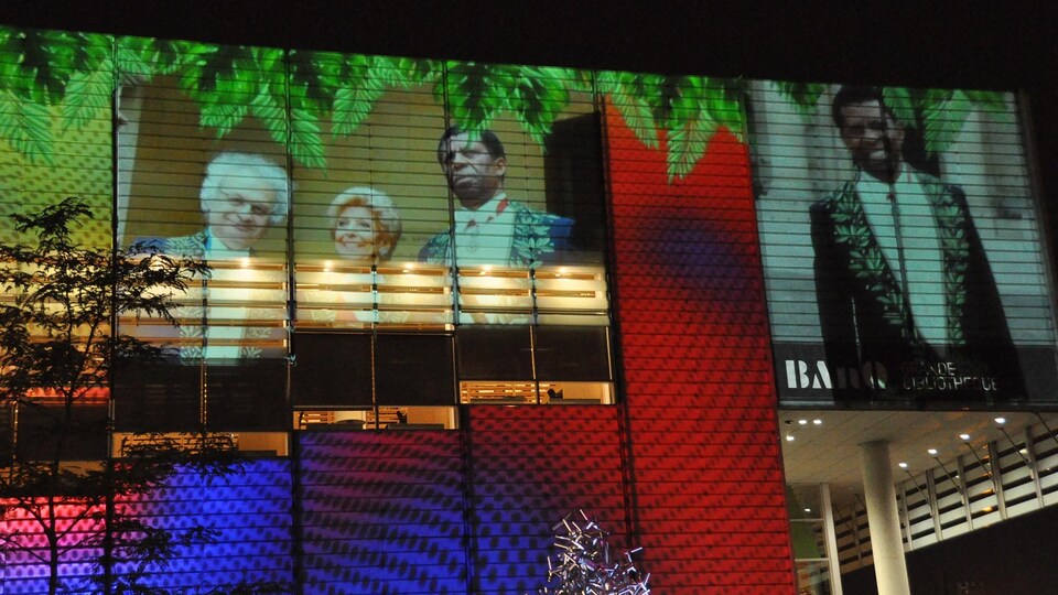 Des photos de Dany Laferrière et des illustrations colorées sont projetées sur un bâtiment.