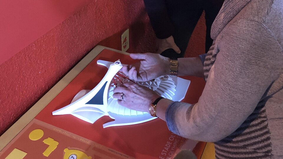 Une personne aveugle touche la maquette tactile du Stade olympique de Montréal pour mieux saisir les particularités architecturales.