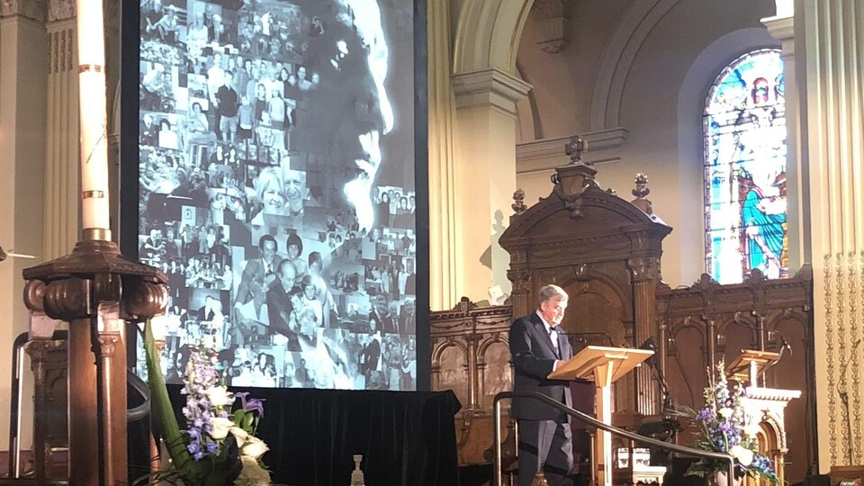 Lucien Bouchard parle devant un écran dans une église.