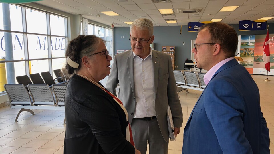 Trois personnes qui discutent dans la salle d'attente de l'aéroport des Îles-de-la-Madeleine