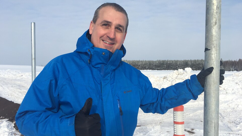Un homme souriant devant un chantier de construction.