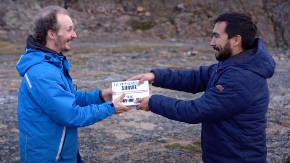 Marc Vachon et Thomassie Mangiok, face à face, tenant une trousse de survie.