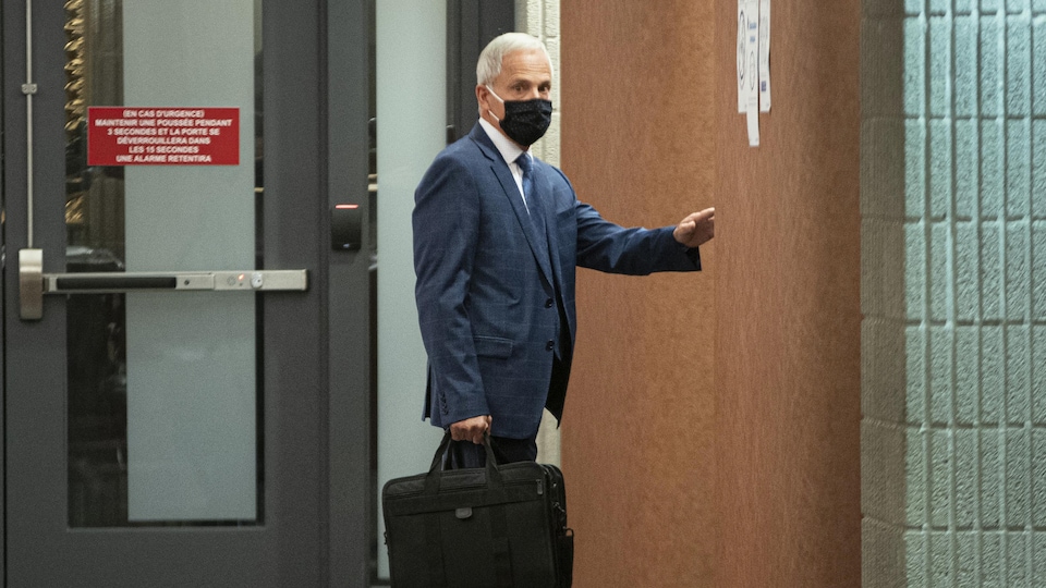 Un homme portant un masque dans un couloir du palais de justice de Montréal.