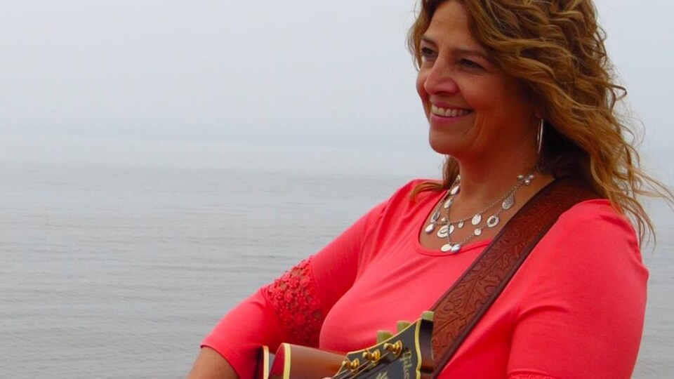 L'auteure-compositrice-interprète Marcella Richard joue la guitare à la plage.