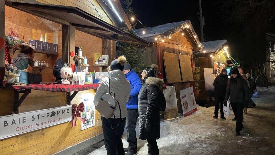 Des  clients s'amassent devant un kiosque au marché de Noël de Baie-Saint-Paul.