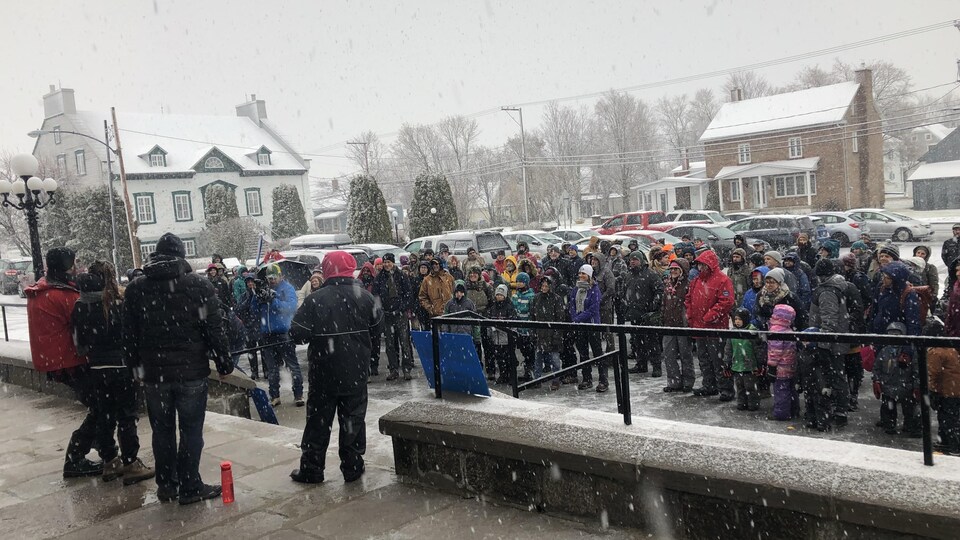 Des dizaines de personnes en habits de neige sont rassemblées devant l'église de Cacouna.