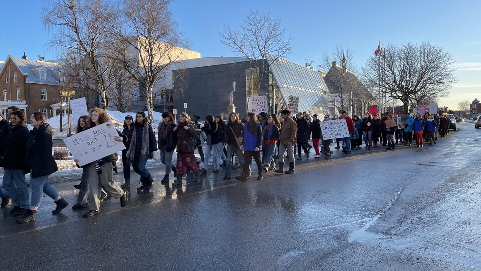 Des manifestants marchent dans la rue en face de la salle Desjardins-Telus.