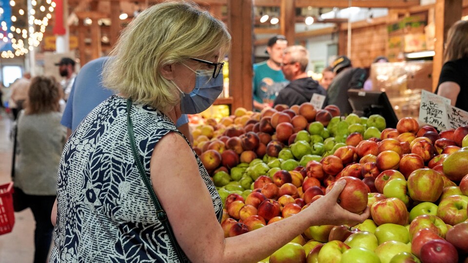 Une femme tient une pomme dans le marché fermier du sud de Calgary, samedi 17 septembre 2022.