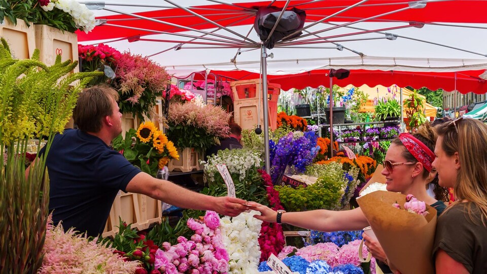 Des personnes achètent des fleurs sur un marché.