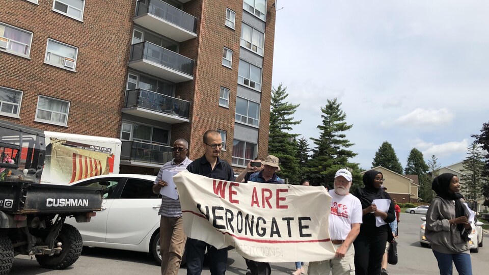 Des manifestants tiennent une affiche où le slogan «We are Heron Gate» («Nous sommes Heron Gate») est inscrit.