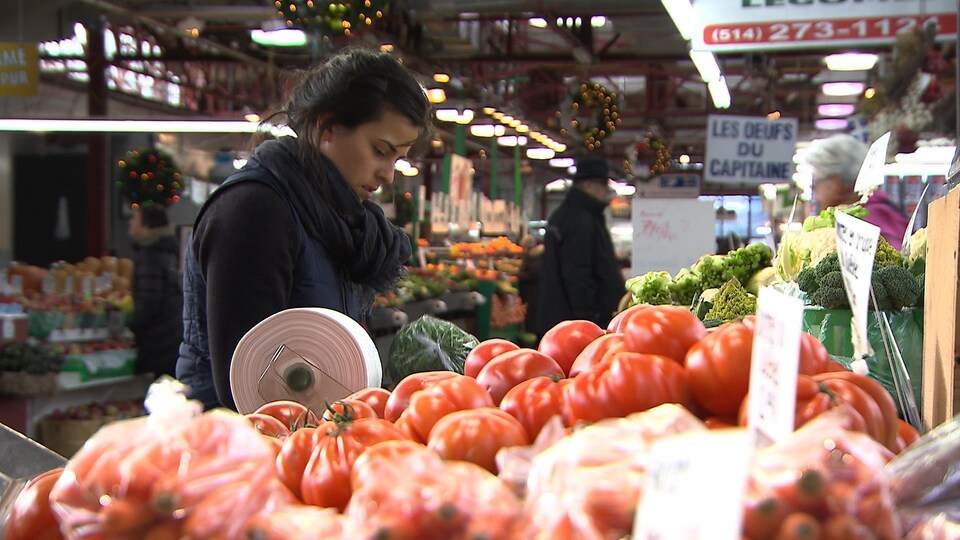 Une jeune femme replace un étal de légumes au marché Jean-Talon, à Montréal.