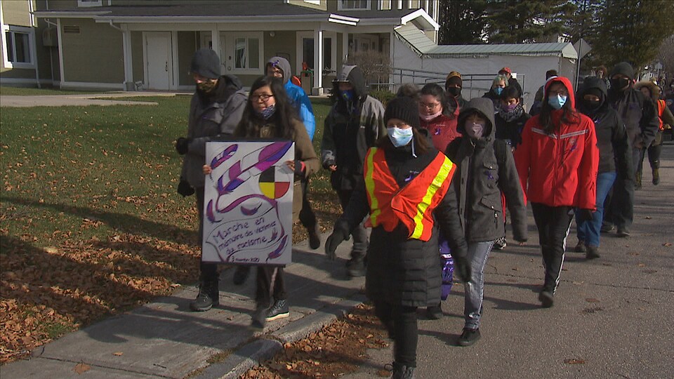 Des personnes marchent dans une rue avec une affiche.