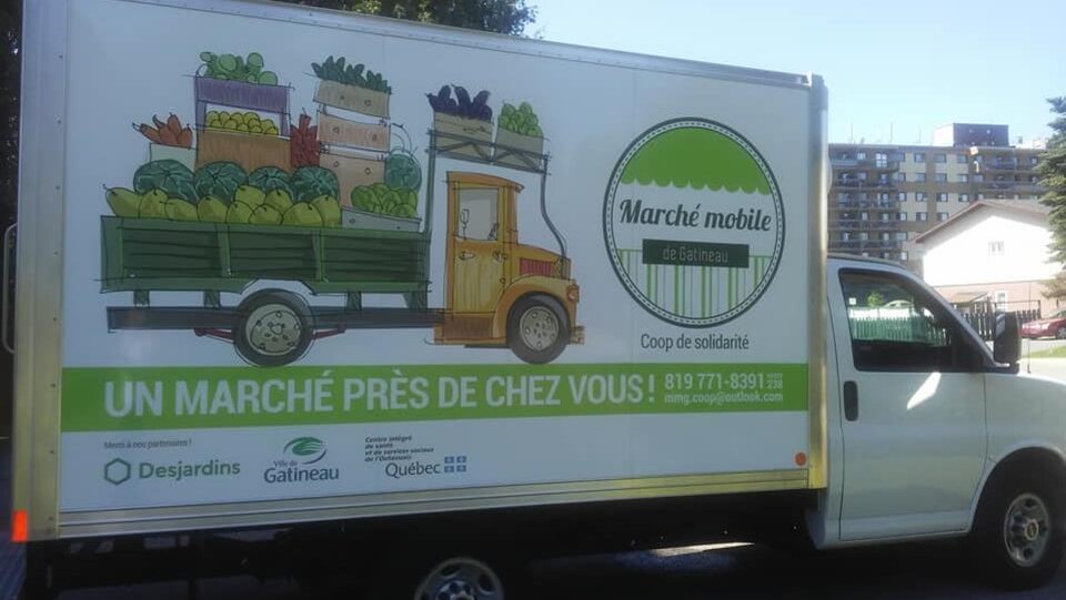 Un camion arborant un logo et une mention disant "Un marché près de chez vous!"