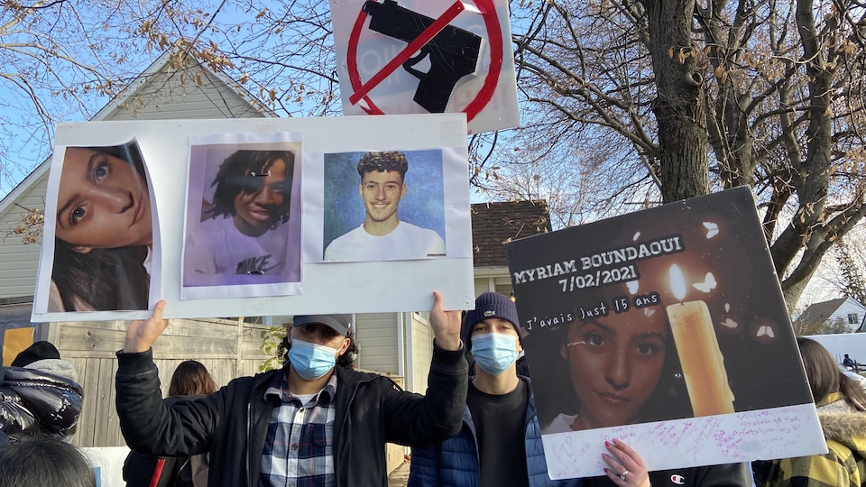 Un homme portant une pancarte représentant des portraits de personnes.