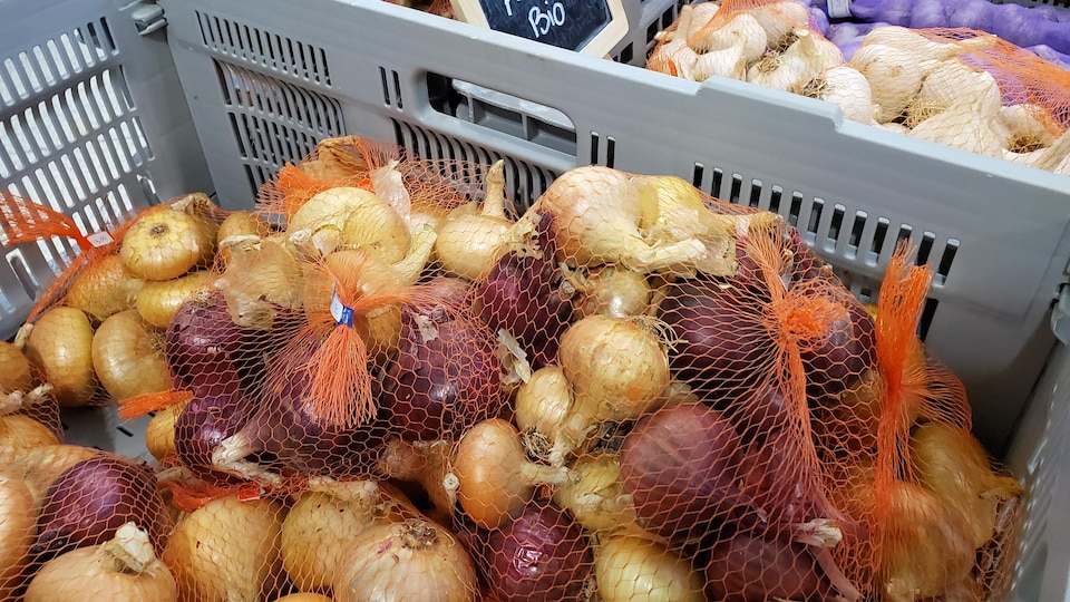 De gros sacs d'oignons dans une épicerie.