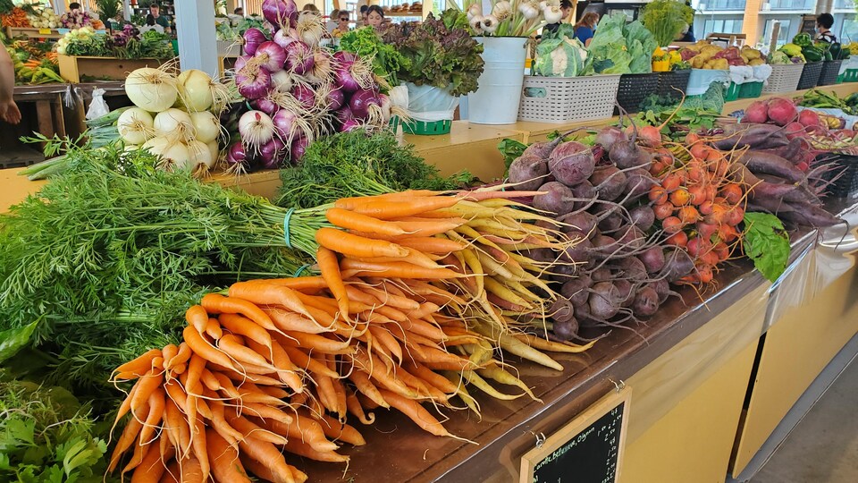 Un étalage de légumes bien garni dans un marché public.