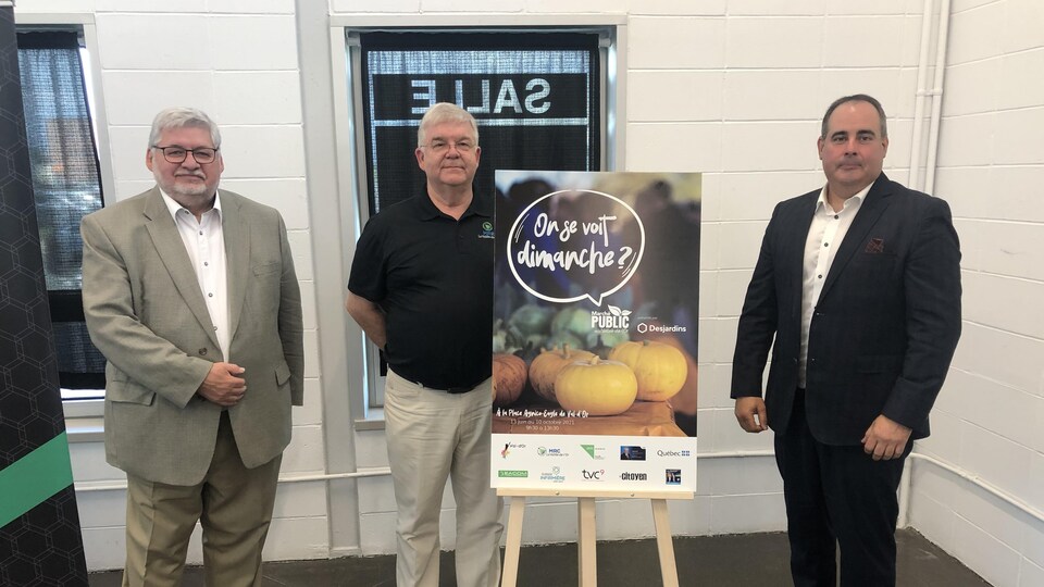 Louis Bourget, Pierre Corbeil et Martin Ferron posent devant la pancarte annonçant le Marché public les dimanches.