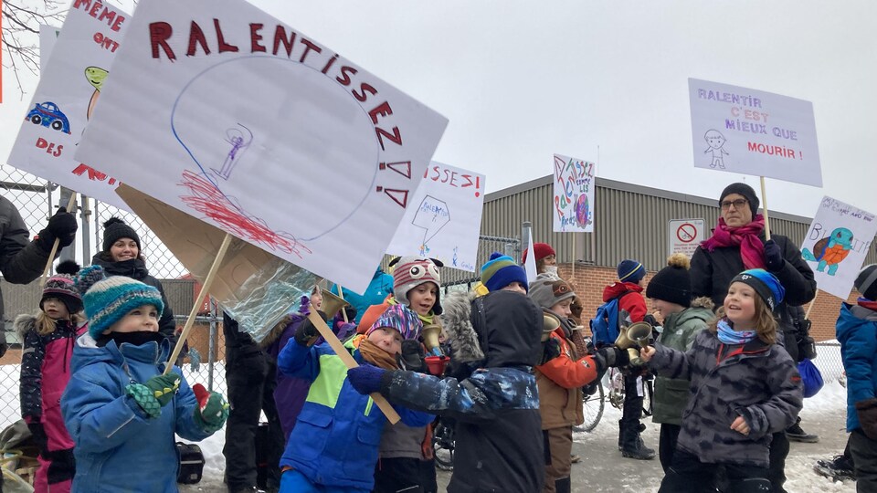 Des enfants et des adultes manifestent devant l'école des Berges, l'hiver.