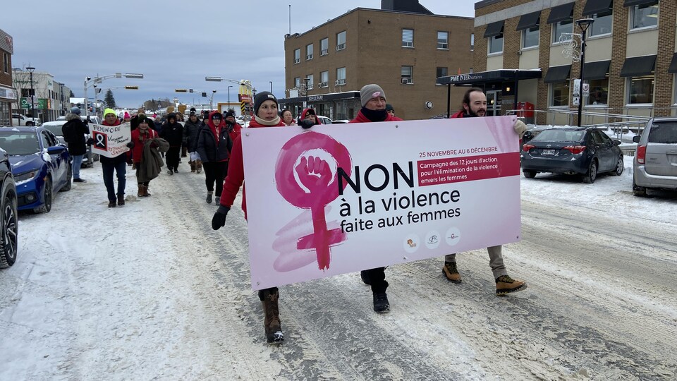 Quelques dizaines de personnes marchent dans la rue, une affiche disant «Non à la violence faite aux femmes» bien en évidence.