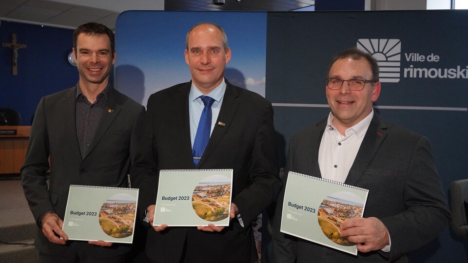 Marco Desbiens, Guy Caron et Sylvain St-Pierre prennent la pose pour une photo avec le document du budget 2023 de la Ville de Rimouski.
