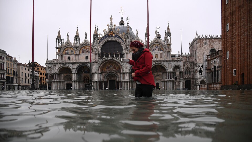 Une femme a de l'eau jusqu'aux genoux devant la basilique.