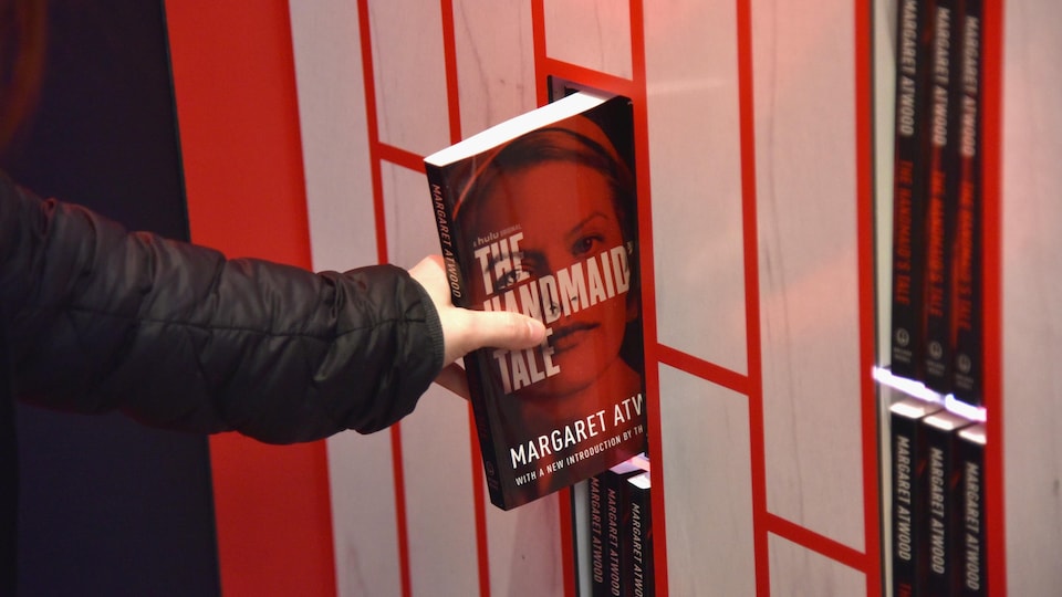 Une main prend un exemplaire du livre « The Handmaid's Tale » sur une tablette.