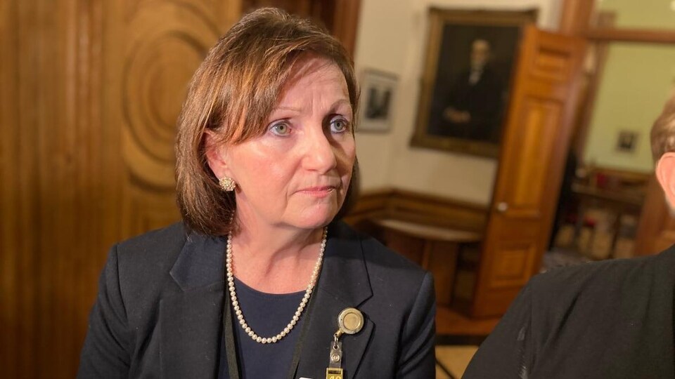 Margaret Melanson en mêlée de presse, entourée de caméras et de micros, dans les corridors de l'édifice de l'Assemblée législative du Nouveau-Brunswick.