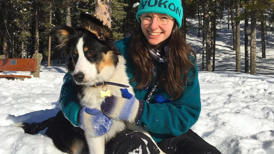 Une jeune femme et son chien dans la forêt du Yukon.