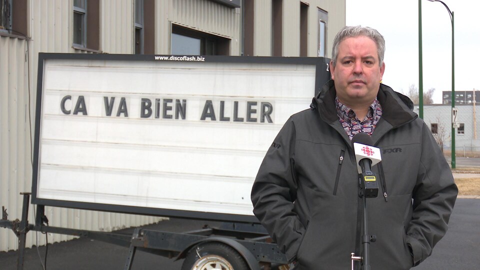 Michaël Ouellet devant un panneau sur lequel est écrit « ça va bien aller. »