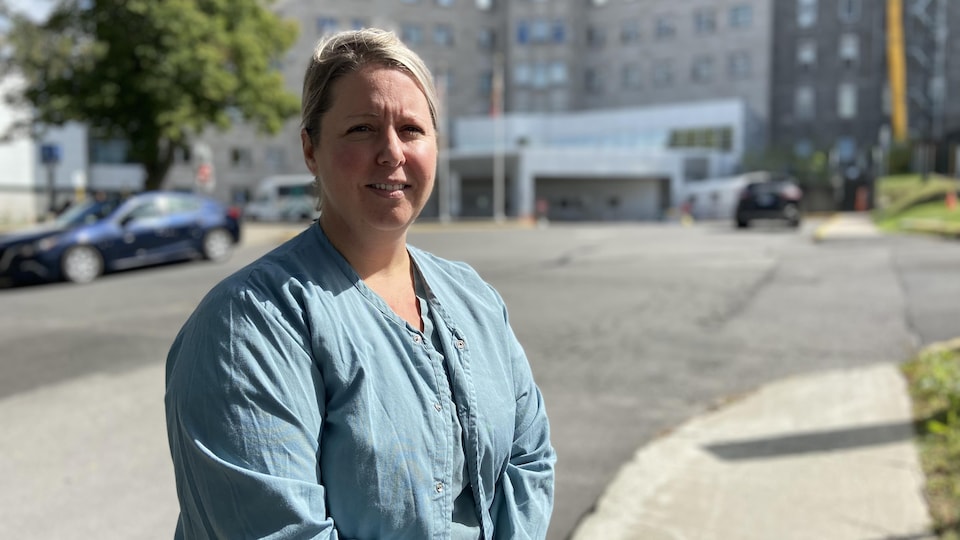 L'infirmière se trouve devant l'entrée principale du centre hospitalier.