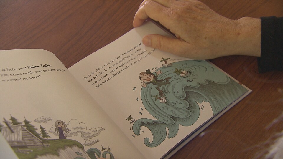 Main tournant une page d'un livre jeunesse sur lequel il y a une illustration d'un homme joyeux marchant sur une vague. 