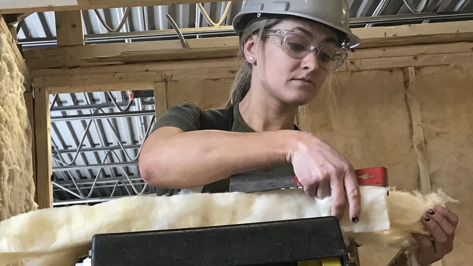 Marie-Ève Lebeau, élève en menuiserie-charpenterie au Centre de formation professionnelle 24-Juin découpe de la laine minérale pour un examen pratique d'isolation de murs.