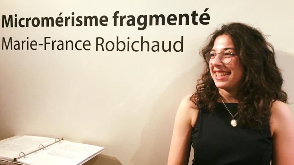 Marie-France Robichaud pose à côté de son nom écrit sur le mur d'une galerie.