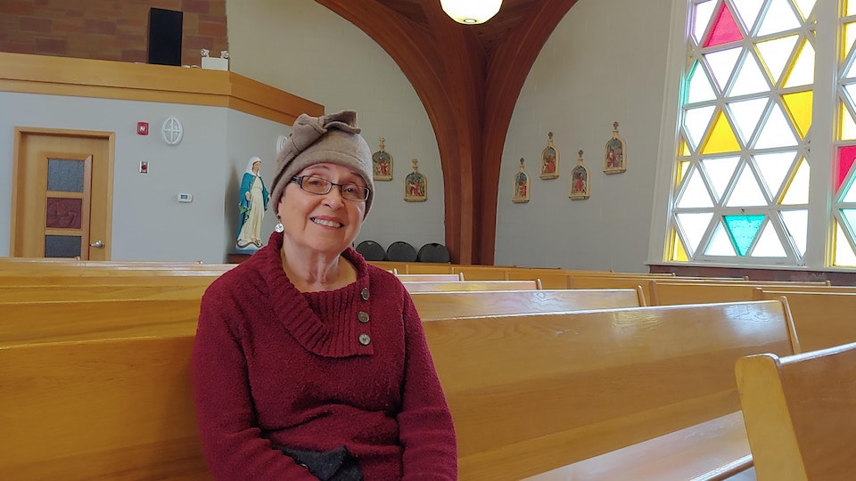 Marie-Jeanne Will est assise sur un banc de l'église Saints-Martyrs-Canadiens.