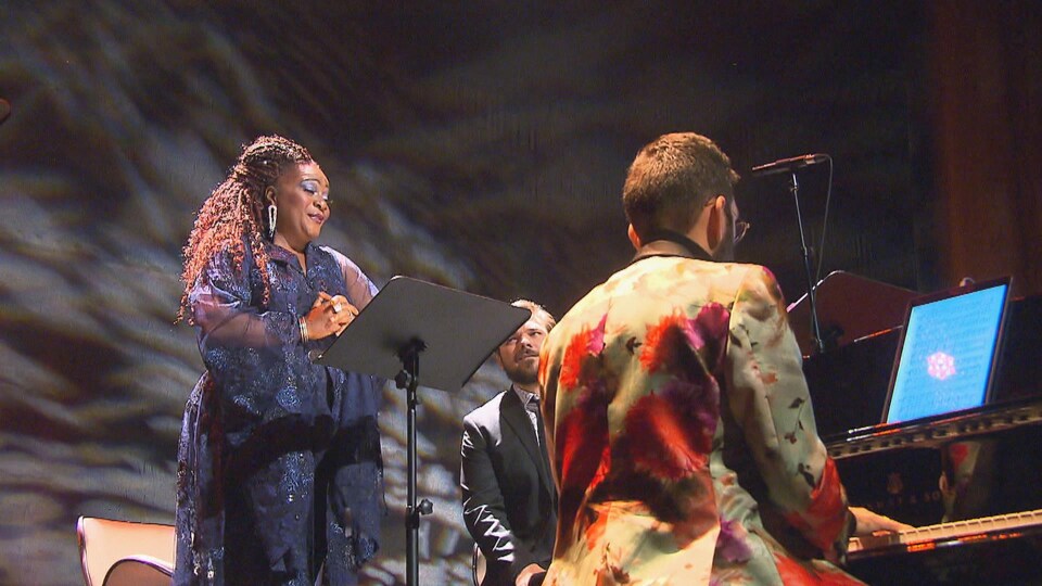 Marie-Josée Lord chante. Au premier plan, un pianiste l'accompagne.
