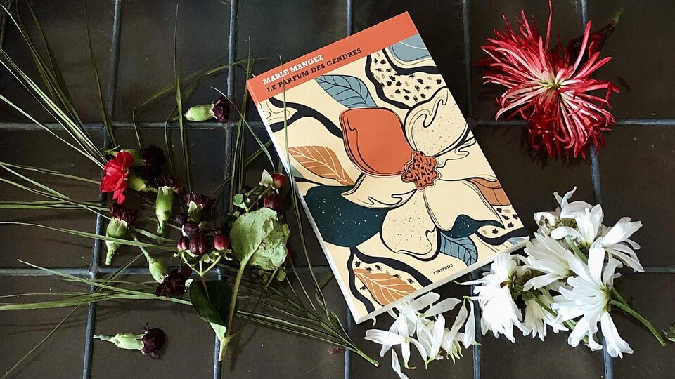 Le livre est déposé parmi des fleurs sur un vitrage carrelé.