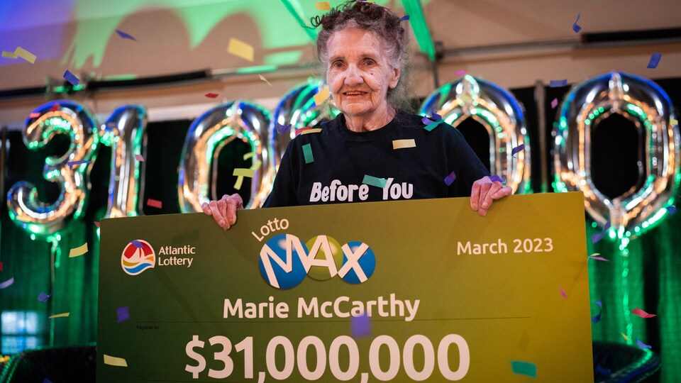 Marie McCarthy tient un chèque géant d'un montant de 31 millions de dollars dans ses mains. 