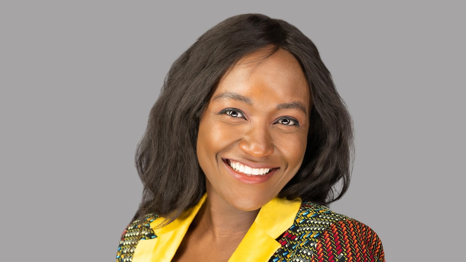Marie Rosette Mikulu porte un veston coloré et affiche un grand sourire.