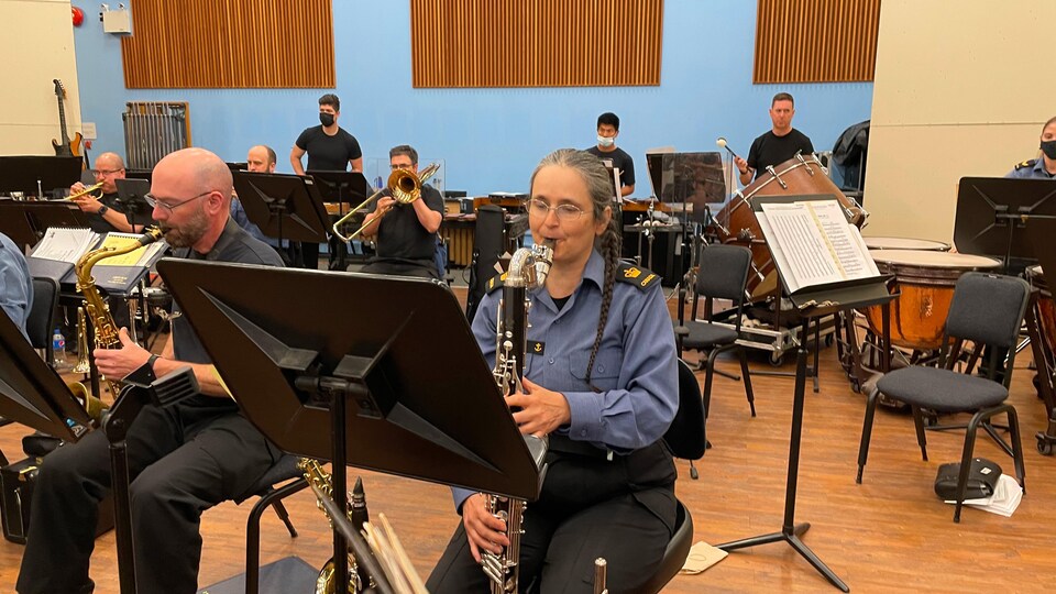 Marielle Audet est en train de jouer de la clarinette basse entourée d'autres membres de l'ensemble de musique qui répètent, le 23 juin 2022.
